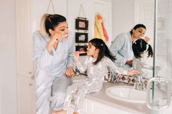 Mujer cepillando los dientes con su hija