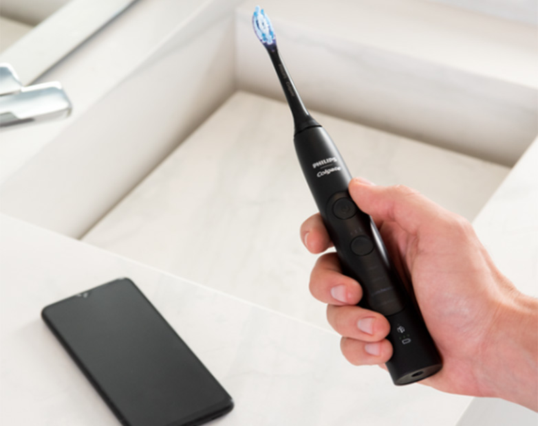 Cepillo de dientes eléctrico junto a smartphone